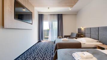 A hotel room with a bed, a desk, a chair, a TV mounted on the wall, and a view of the outdoors.