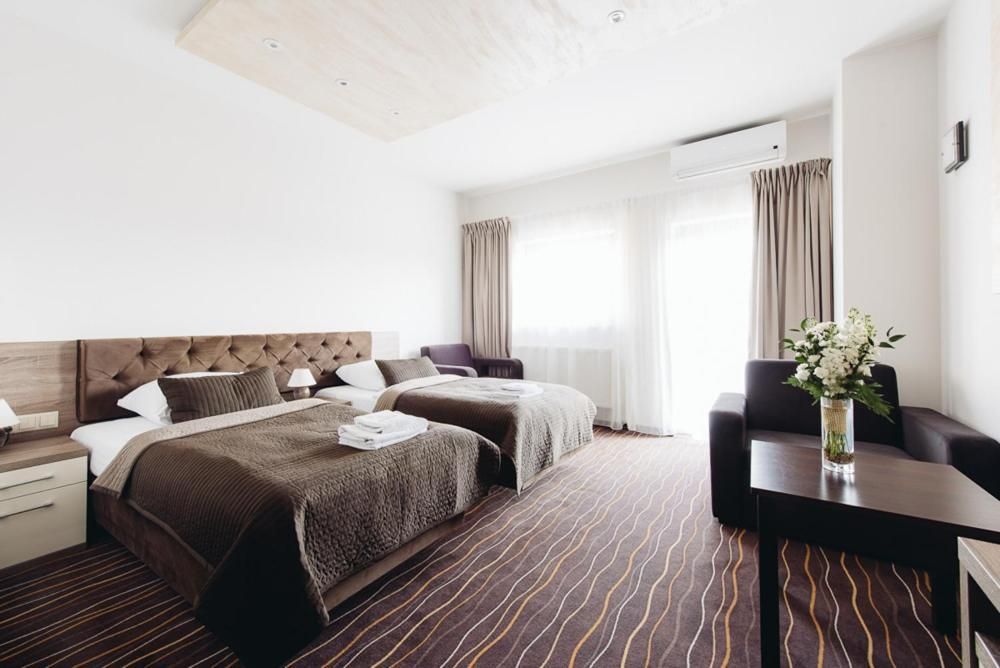 A hotel room with a large bed, two bedside tables, a desk, and a chair.