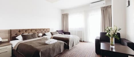 A hotel room with a large bed, two bedside tables, a desk, and a chair.