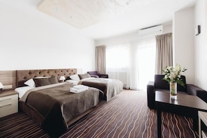 Una habitación de hotel con una cama grande, dos mesitas de noche, un escritorio y una silla.