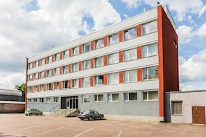 A multi-story building with a parking lot in front. - Ehe Hostel (Tallinn)