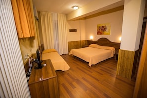 Una habitación de hotel con dos camas, un escritorio y una ventana con cortinas.