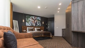 Una habitación de hotel con una cama grande, un sofá, un armario y un cuadro en la pared.
