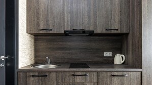 Cocina compacta con un lavamanos, hervidor y cafetera sobre la encimera.