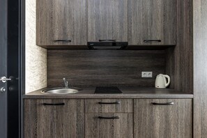 Cozinha compacta com pia, chaleira e cafeteira no balcão.