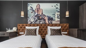 Habitación de hotel con una cama grande, dos mesitas de noche, un cuadro en la pared y lámparas colgantes.