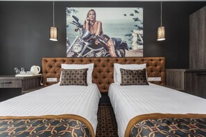 Quarto de hotel com uma cama grande, duas mesas de cabeceira, um quadro na parede e luminárias pendentes.