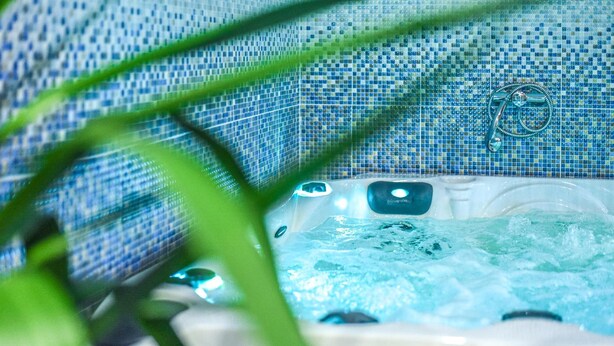 Un jacuzzi con pared de azulejos y un grifo.