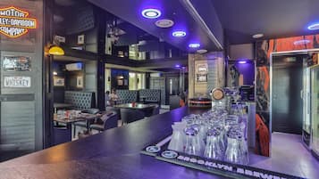 A bar area with a counter, glasses, and a neon sign.