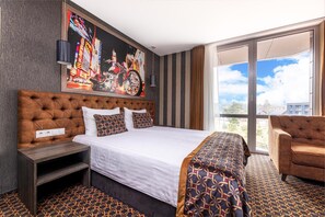 Habitación de hotel con una cama grande, un área de descanso, un cuadro en la pared y vistas a través de la ventana.