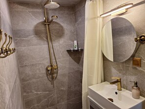 Un baño con ducha, lavamanos y espejo.