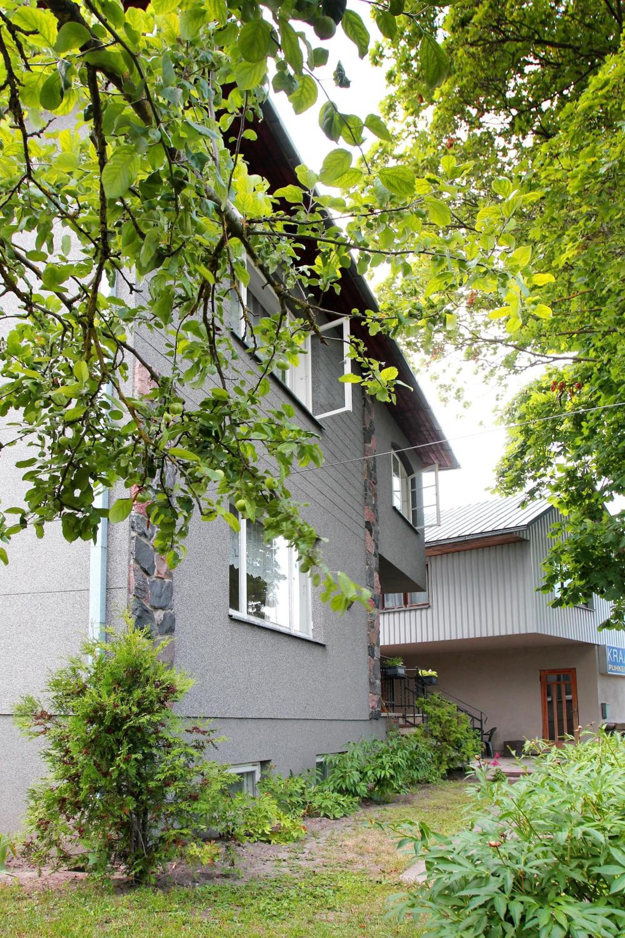 A two-story building with a stone facade, a small garden area, and a visible balcony.