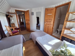 Habitación de hotel con dos camas, un armario de madera, un espejo, una silla y una mesita.