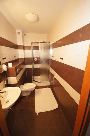 Baño pequeño con ducha, inodoro y lavamanos.