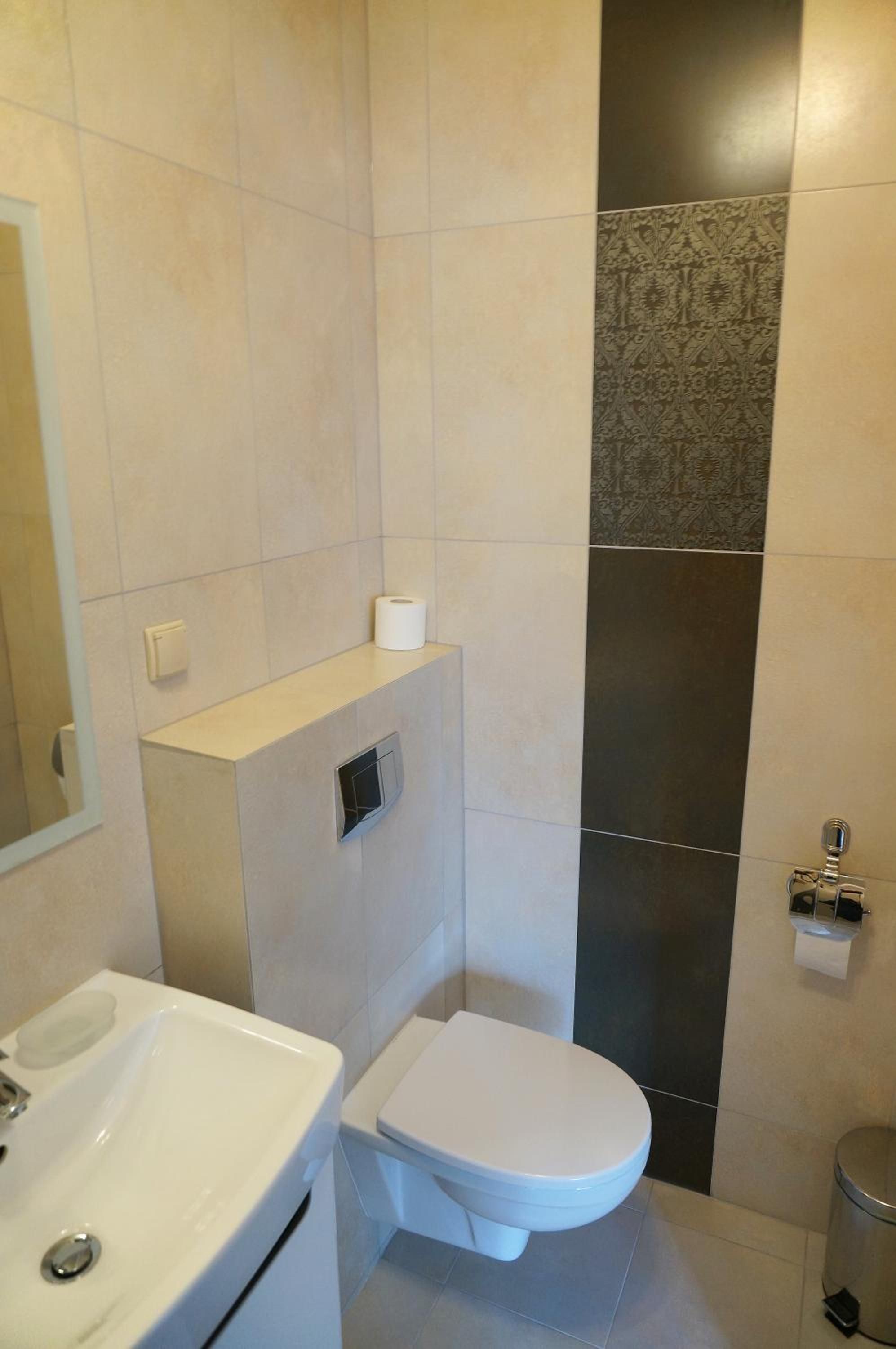A bathroom with a toilet, a sink, and a trash bin.
