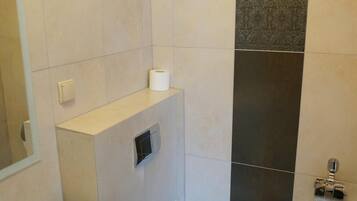 A bathroom with a toilet, a sink, and a trash bin.