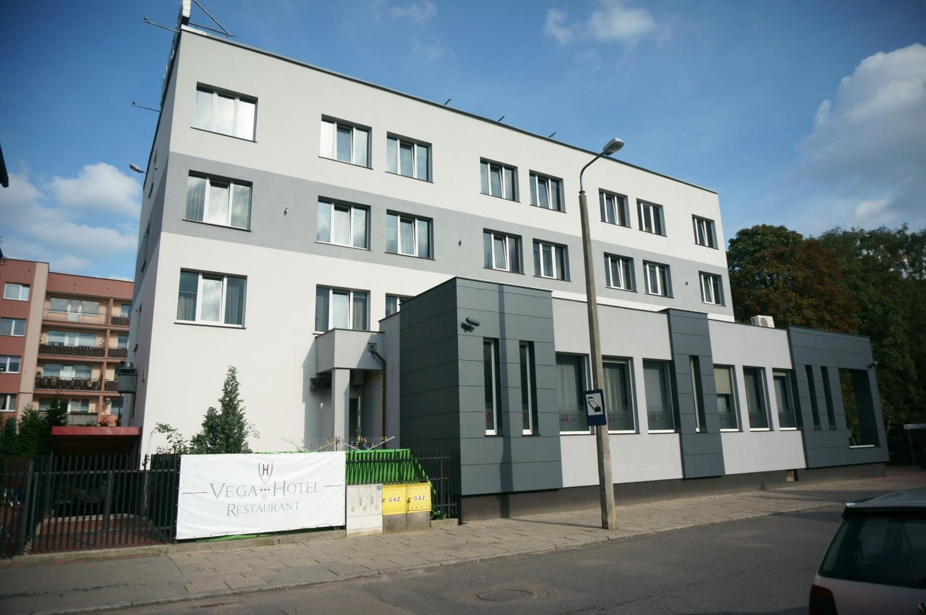 A modern building with multiple windows, a sign for a restaurant, and a street lamp.