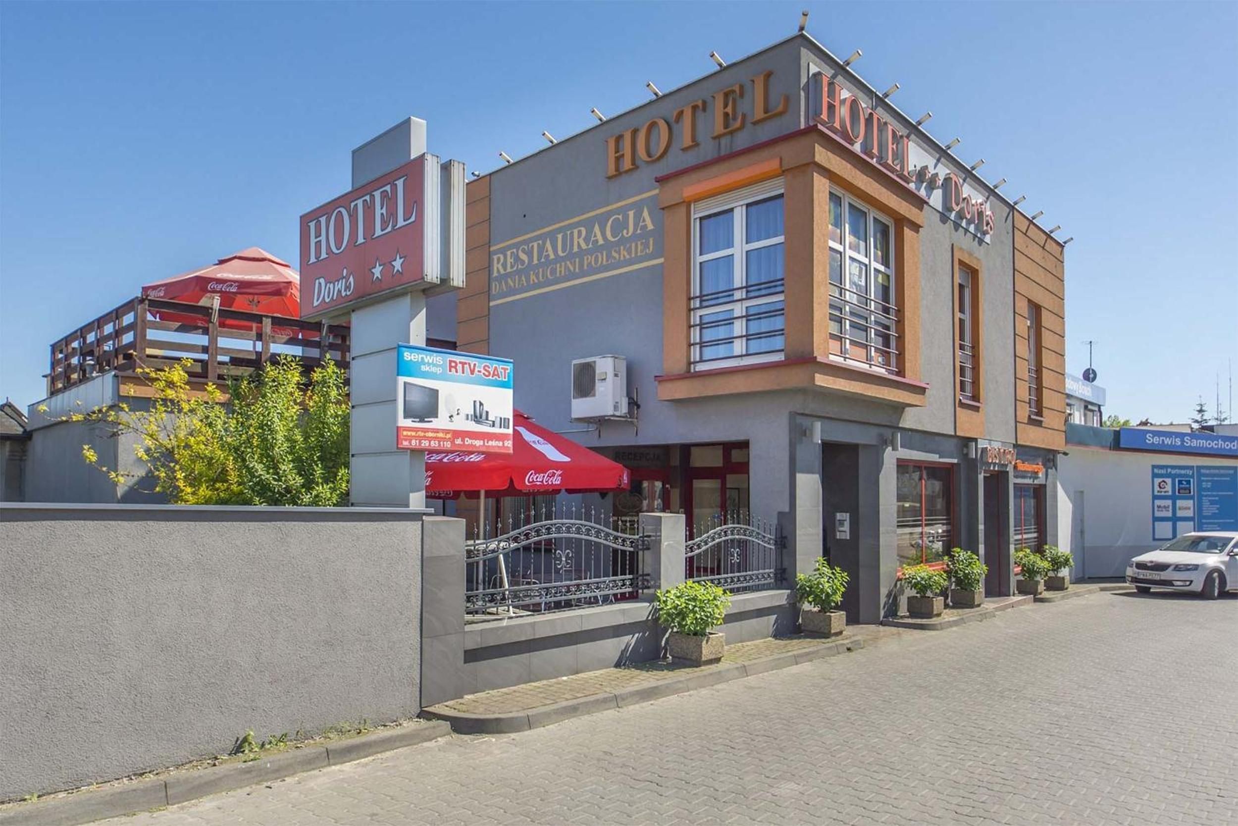 Un hotel con un cartel que dice 'HOTEL DORIS' y 'RESTAURACJA DANIA KUCHNI POLSKIEJ', indicando un restaurante en su interior.