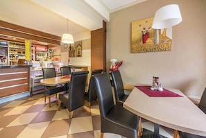 A restaurant with a bar area, black leather chairs, and a table with a red placemat. - Hotel Doris (Oborniki)