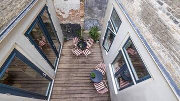 Une terrasse sur le toit avec une plateforme en bois, une table ronde et des chaises roses.