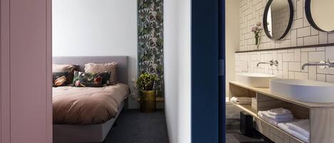 Un dormitorio moderno con cama, mesita de noche y espejo montado en la pared.