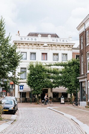 A hotel with a sign reading 'STADSHOTEL' and a cyclist passing by. - Stadshotel Steegoversloot (Dordrecht)