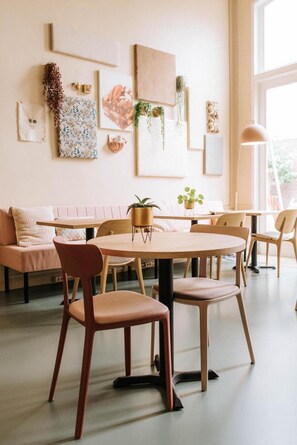 A modern interior with a round dining table, cushioned chairs, a sofa, and artwork on the walls. - Stadshotel Steegoversloot (Dordrecht)