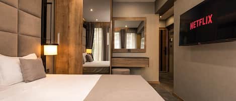 A modern hotel room with a large bed, a TV mounted on the wall, and a wooden panel design.