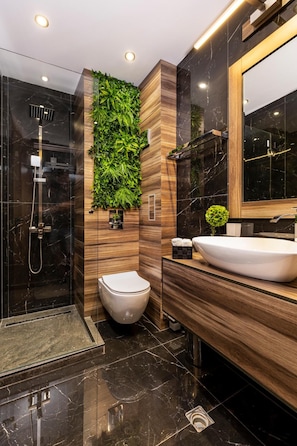 A modern bathroom with a glass-enclosed shower, a wooden vanity, and a green vertical garden. - Soho Apart House (Plovdiv)