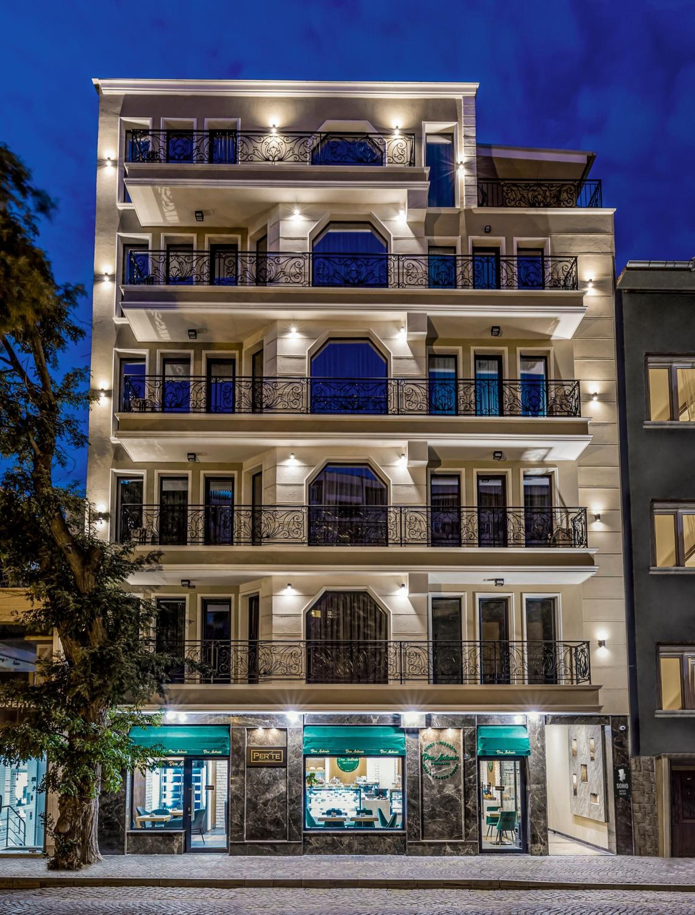 Un hôtel à plusieurs étages doté de balcons, d’un restaurant situé au rez-de-chaussée et d’une façade en pierre.