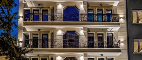 Un hôtel à plusieurs étages doté de balcons, d’un restaurant situé au rez-de-chaussée et d’une façade en pierre.