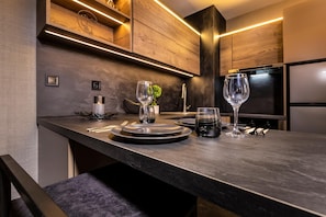 A modern kitchen with a dark countertop, wooden cabinets, and built-in appliances. - Soho Apart House (Plovdiv)