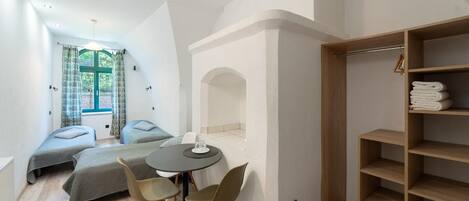 A compact room with a bed, two chairs, a table, and a wooden wardrobe.