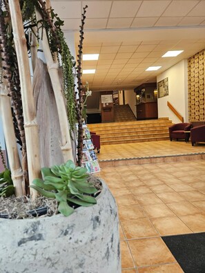 Um hall de hotel com balcão de recepç ão, escada e área de estar.