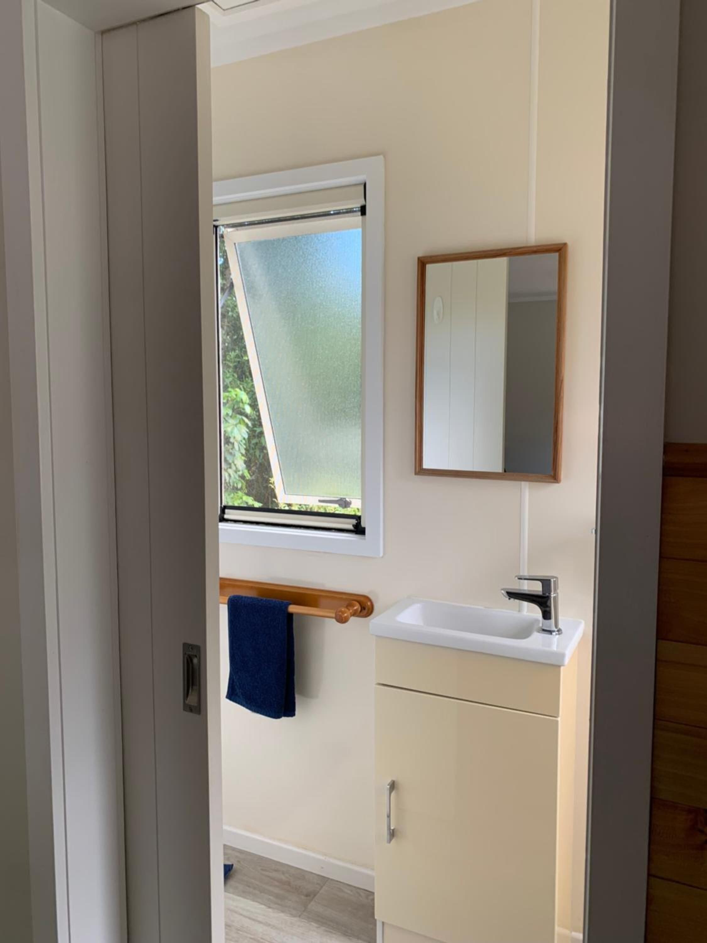 A bathroom with a window, a sink, and a mirror.