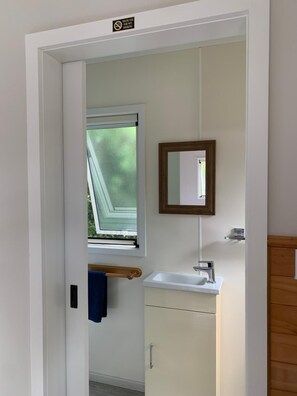 Un baño con ventana, lavamanos, espejo y toallero.