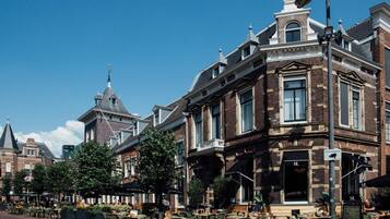 Een historisch gebouw met een opvallende hoentering, grote ramen en een klassieke baksteenvoorgevel.