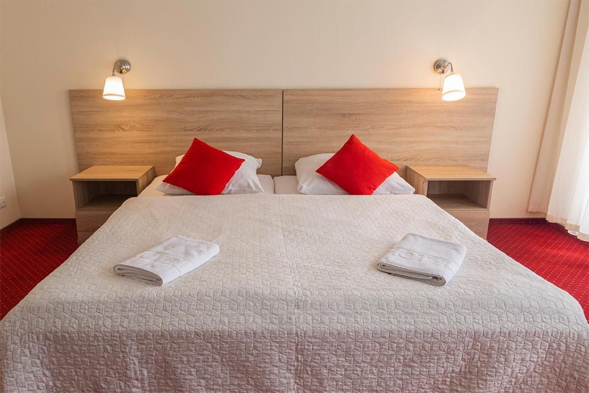 Ein Hotelzimmer mit einem großen Bett, zwei Nachttischen und einem Holzkopfende.