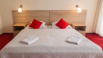 A hotel room with a large bed, two nightstands, and a wooden headboard.
