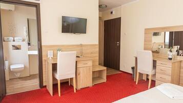 A hotel room with a bed, a desk, a chair, a television, and a bathroom.