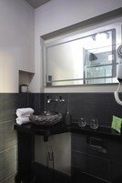 Un baño moderno con un lavamanos negro, un espejo y un secador de pelo.