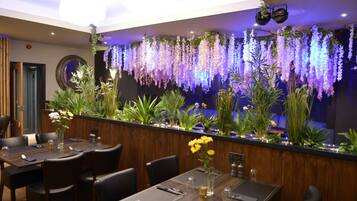 Un interior de restaurante con una barra larga, varias mesas y sillas.