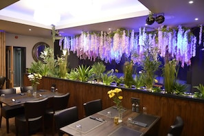 Un interior de restaurante con una barra larga, varias mesas y sillas.
