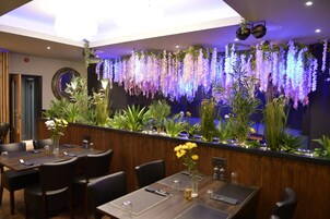 Un interior de restaurante con una barra larga, varias mesas y sillas.