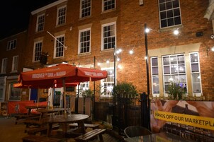A brick building with outdoor seating and string lights.
