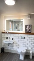 Un baño con lavamanos blanco, inodoro y espejo sobre el lavamanos.