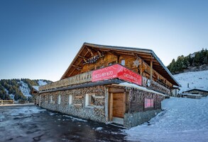 Un chalé de madera con fachada de piedra, un balcón de madera y un cartel que indica que es un restaurante.