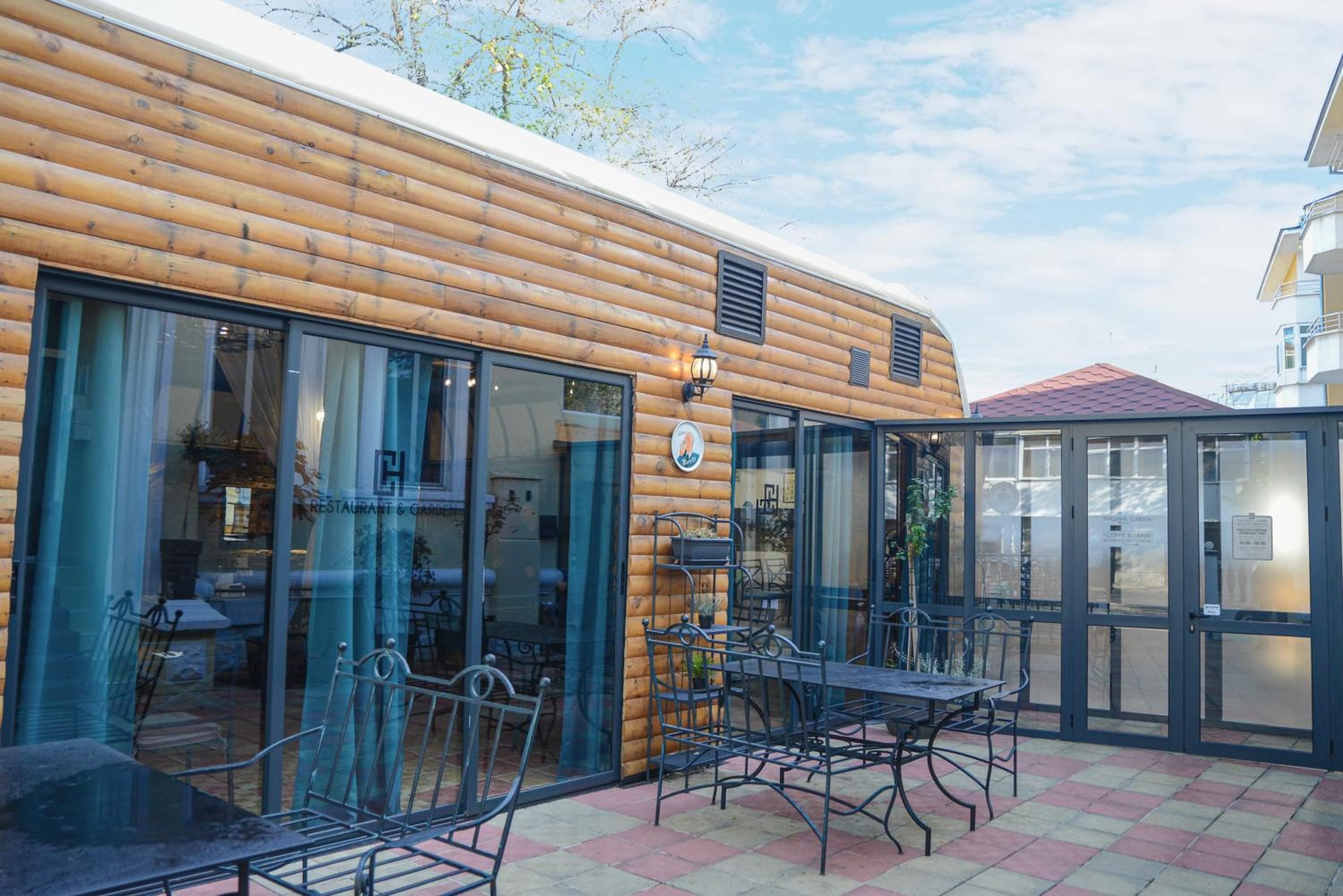 A wooden building with large windows and a patio area with outdoor seating.