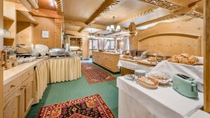 Ein Holzinterieur mit einer Buffetauslage, darunter ein Büfett, ein Servierebereich und eine Küche im Hintergrund.