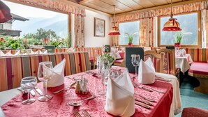 Ein Restaurant mit Blick auf die Berge, mit gestreifter Polsterung und roten Tischtüchern.